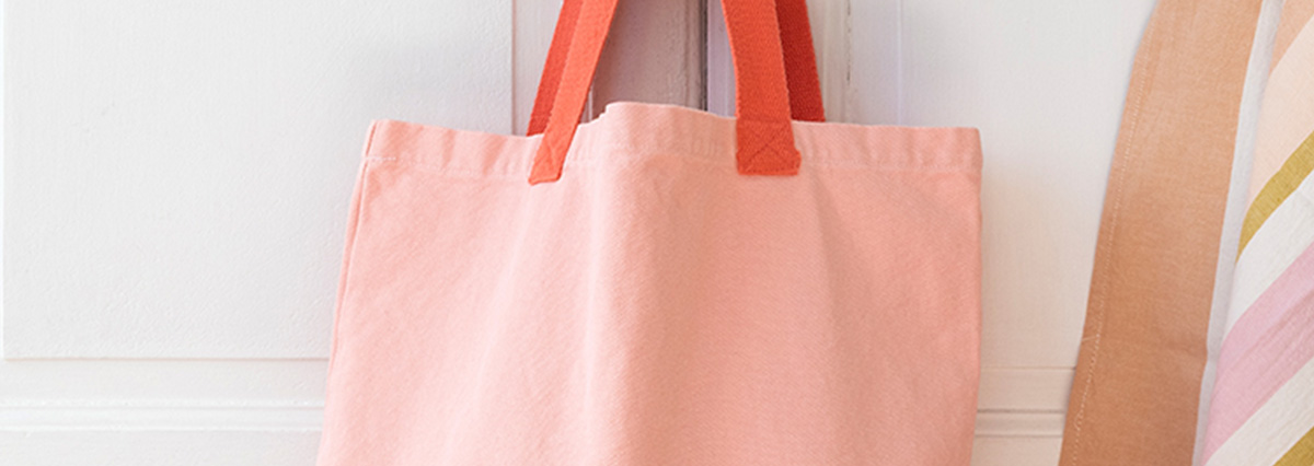 A cotton tote bag with body and handles in different shades of pink. 