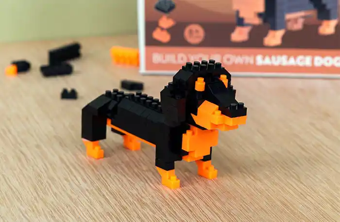 A small black and orange block-style model of a dachshund (sausage dog) made from interlocking bricks.