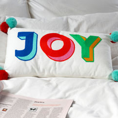 besticktes kissen mit pompons – joy