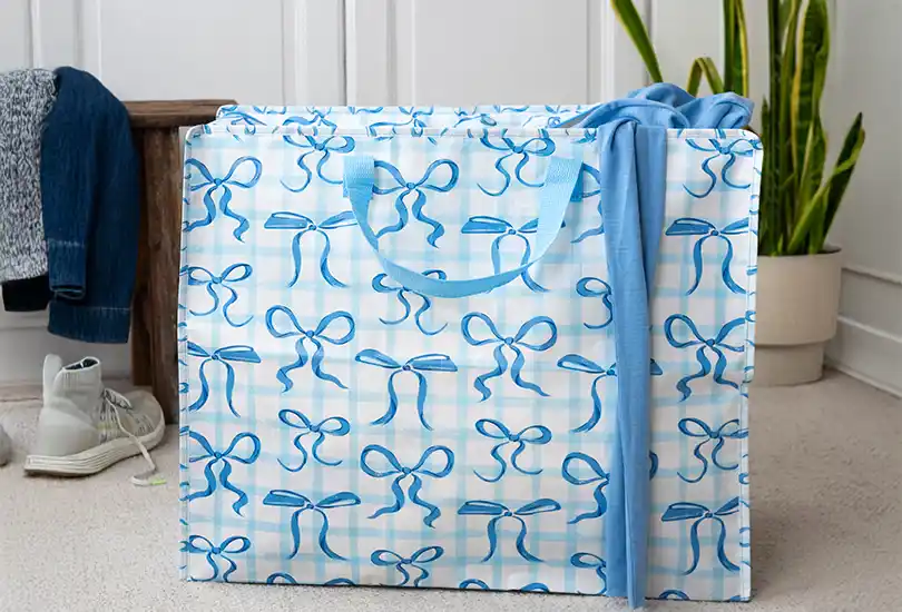 A  jumbo bag - featuring a faint blue gingham pattern on a white background, accented by a scattering of pretty blue bows.