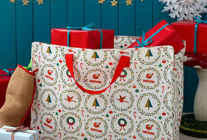 Jumbo storage bag in white, featuring a classic yuletide design that boasts an abundance of cheerful festive imagery: robins, Christmas trees, baubles, candy canes, holly wreaths and more.