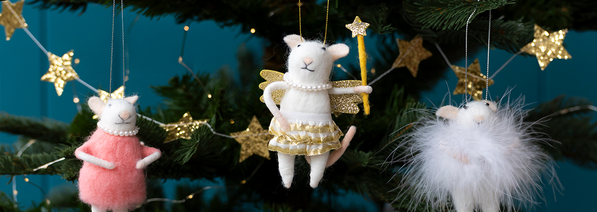 Three mouse ornaments hanging on a Christmas tree: one in a pink dress with a pearl necklace, one dressed as an angel with golden wings and a star wand, and one in a fluffy white outfit, surrounded by green branches and golden stars.
