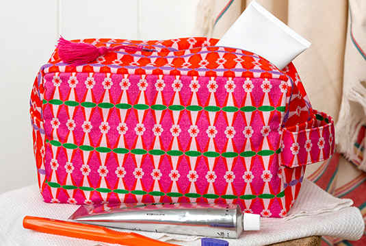 Bright pink patterned toiletry bag with multicolour geometric design.