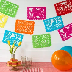 Colorful paper bunting with intricate cut-out designs, including elephants, birds, and floral patterns. The bunting features rectangles in green, pink, red, orange, and blue. Colorful paper bunting with intricate cut-out designs, including elephants, birds, and floral patterns. The bunting features rectangles in green, pink, red, orange, and blue.