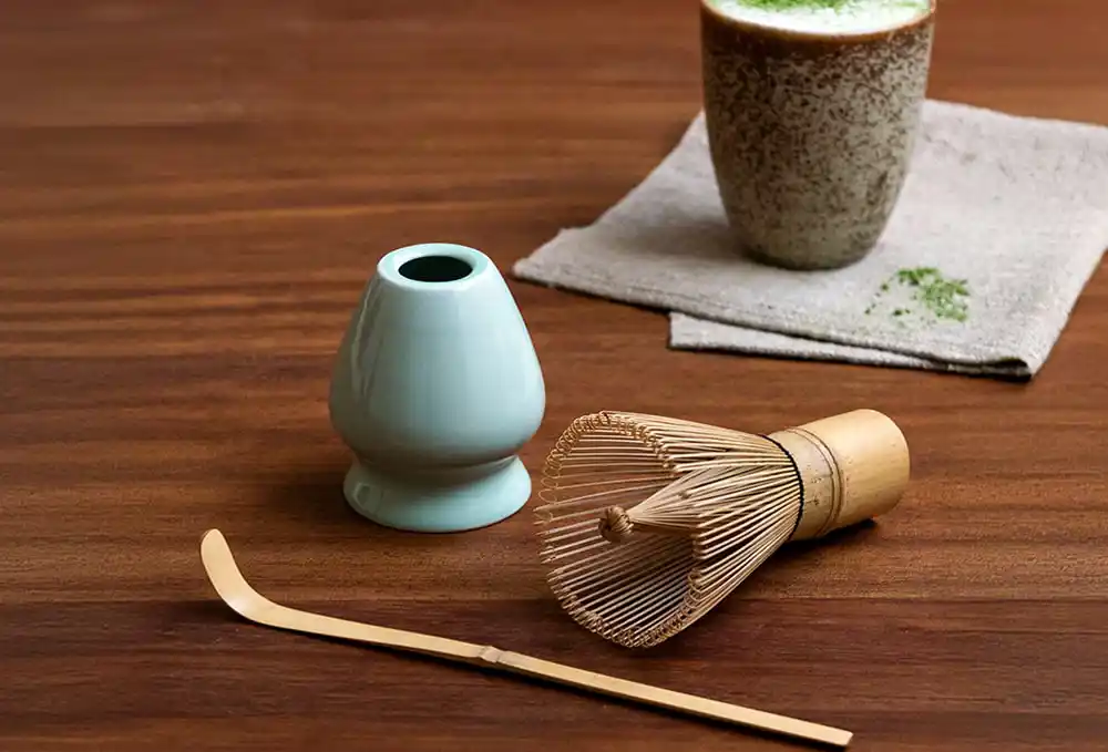 Matcha tea preparation set, including a bamboo whisk (chasen), a light blue ceramic whisk holder, a bamboo scoop (chashaku)