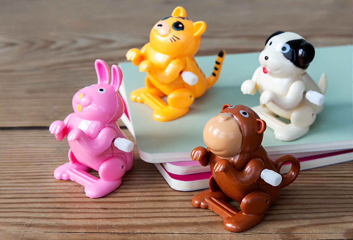 Four small animal wind up toys - a yellow cat, white dog, pink rabbit, and brown monkey