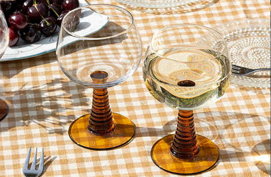 Set of 2 Amber roemer glasses on a checkered tablecloth next to cutlery and plates